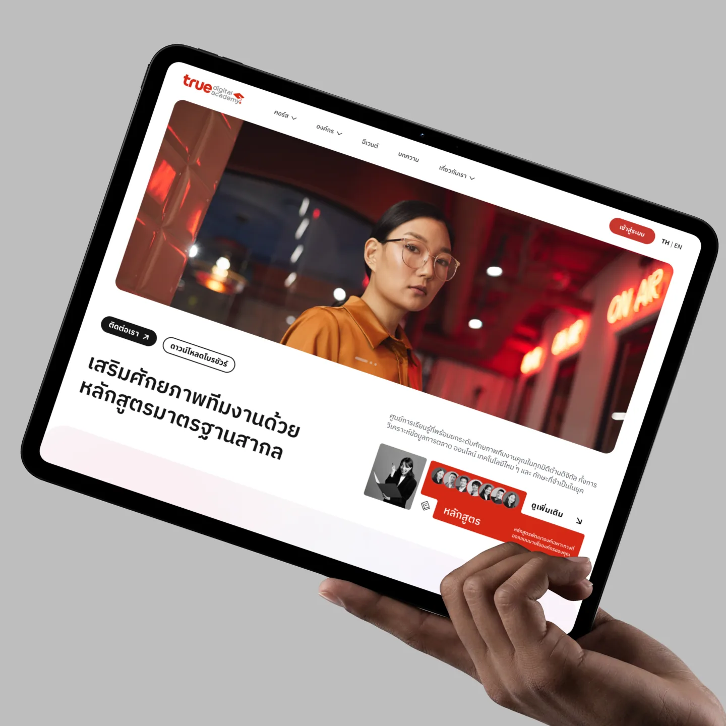 A hand holding a tablet open on the Thai-language page for businesses, which offers teams courses built to international standards